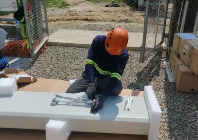 Worker assembling a white equipment component at a telecom site