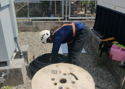 Worker handling equipment beside a cable spool at a telecom site