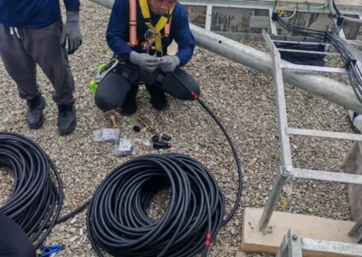 Worker handling cables and tools at a telecom site