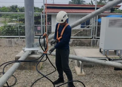 Worker handling cable beside a telecom tower