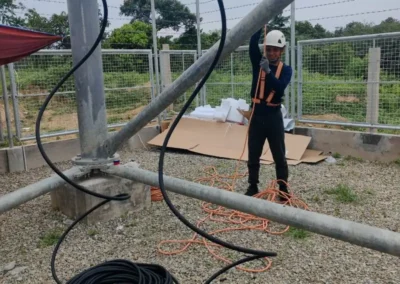 Worker handling cable beneath a telecom tower