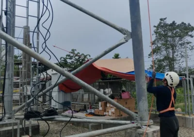 Worker handling cable near the base of a telecom tower